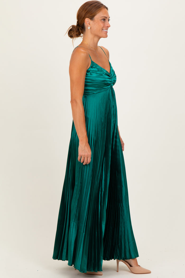 woman wearing a pleated emerald green maxi dress with spaghetti straps and a twist front detail