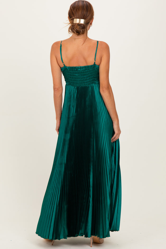 woman wearing a long emerald green pleated maxi dress with spaghetti straps and a smocked back