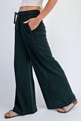 woman wearing black wide-leg lounge pants with pockets and a drawstring waist