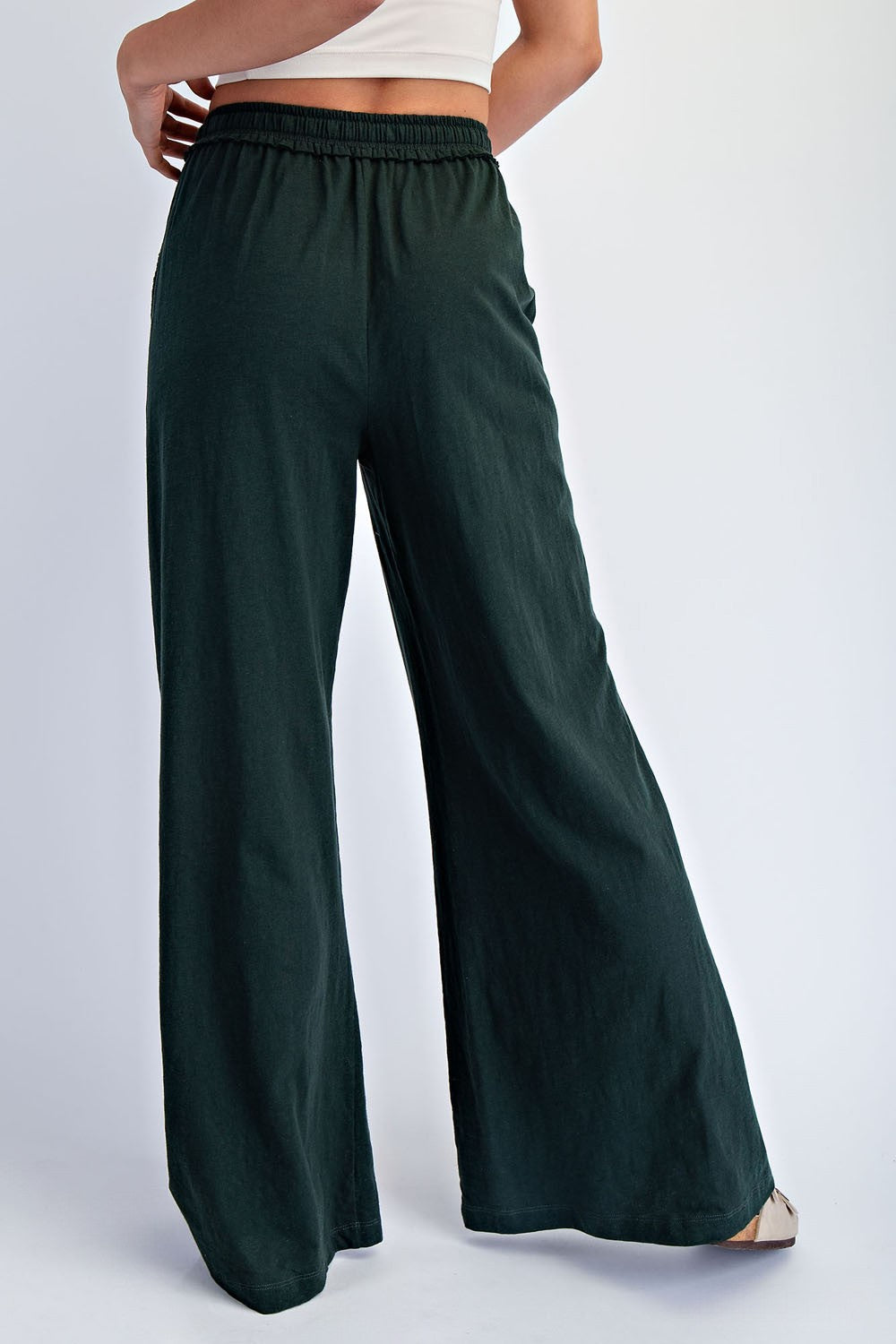 woman wearing dark green wide-leg pants with an elastic waistband, seen from the back