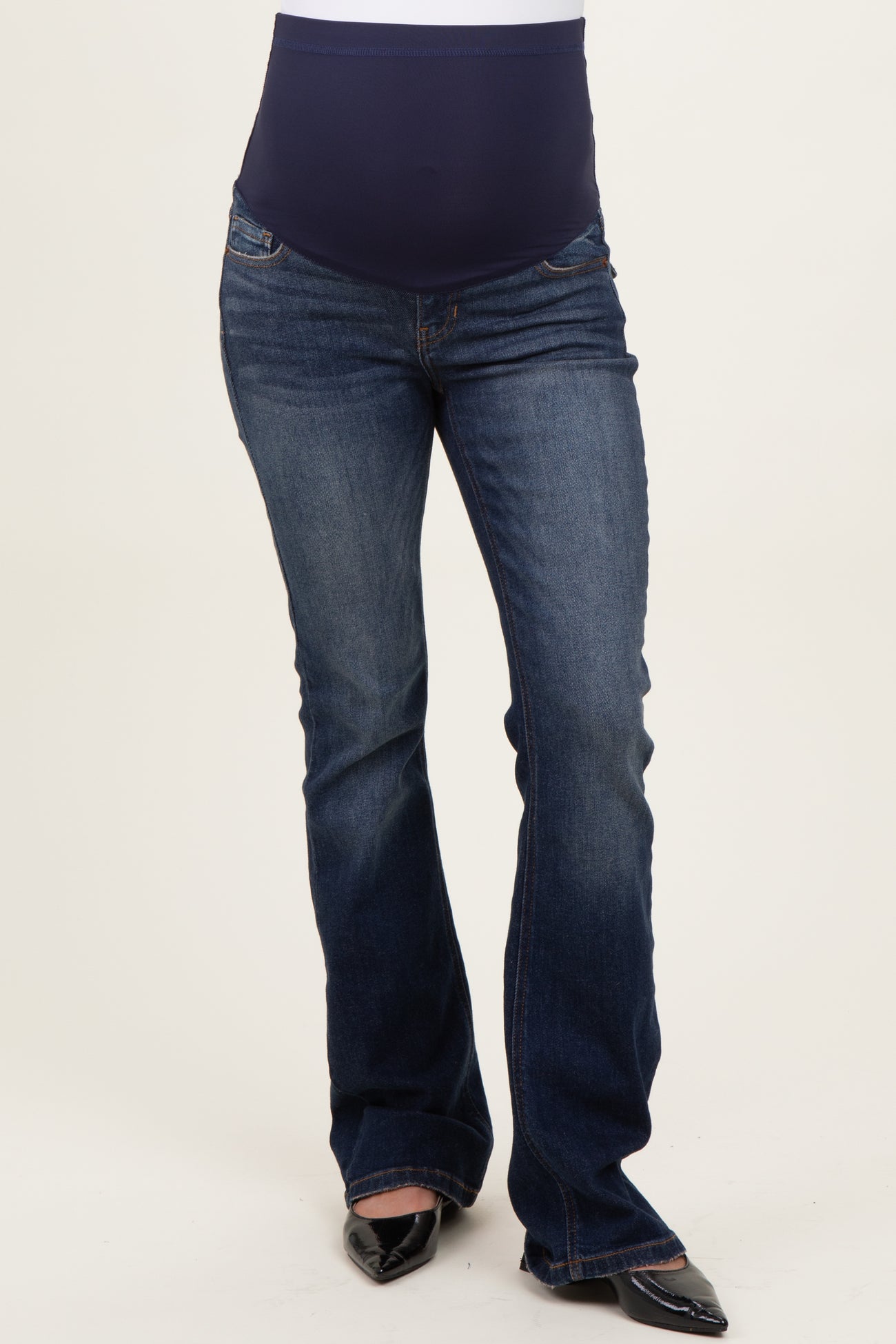 woman wearing dark blue maternity bootcut jeans with a stretchy navy waistband and flared leg design, showing her baby bump