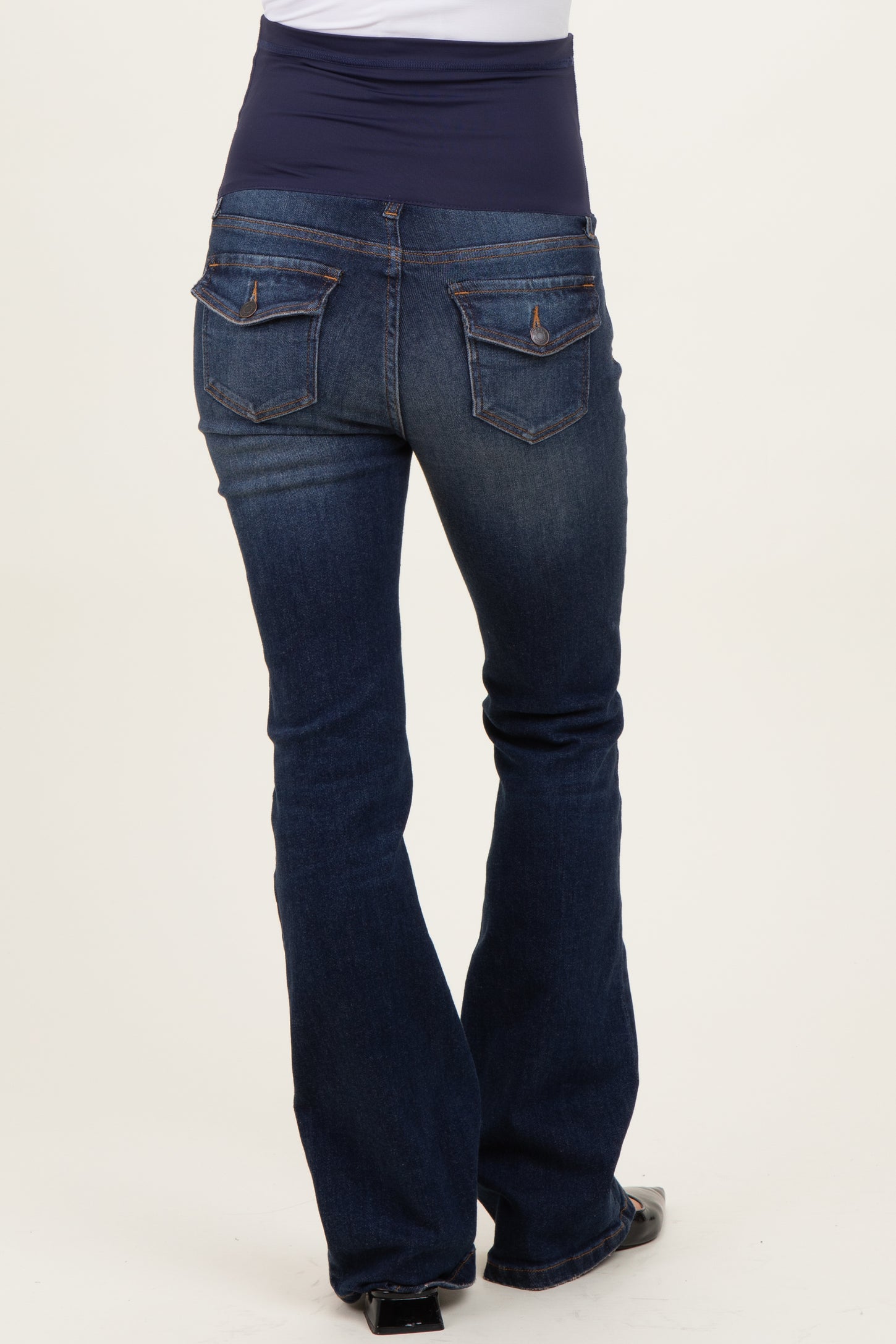 woman wearing dark blue maternity bootcut jeans with a navy underbelly panel, showing the back view