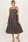 woman wearing a green and red plaid maternity dress with tie straps and a scalloped hem, showcasing her baby bump