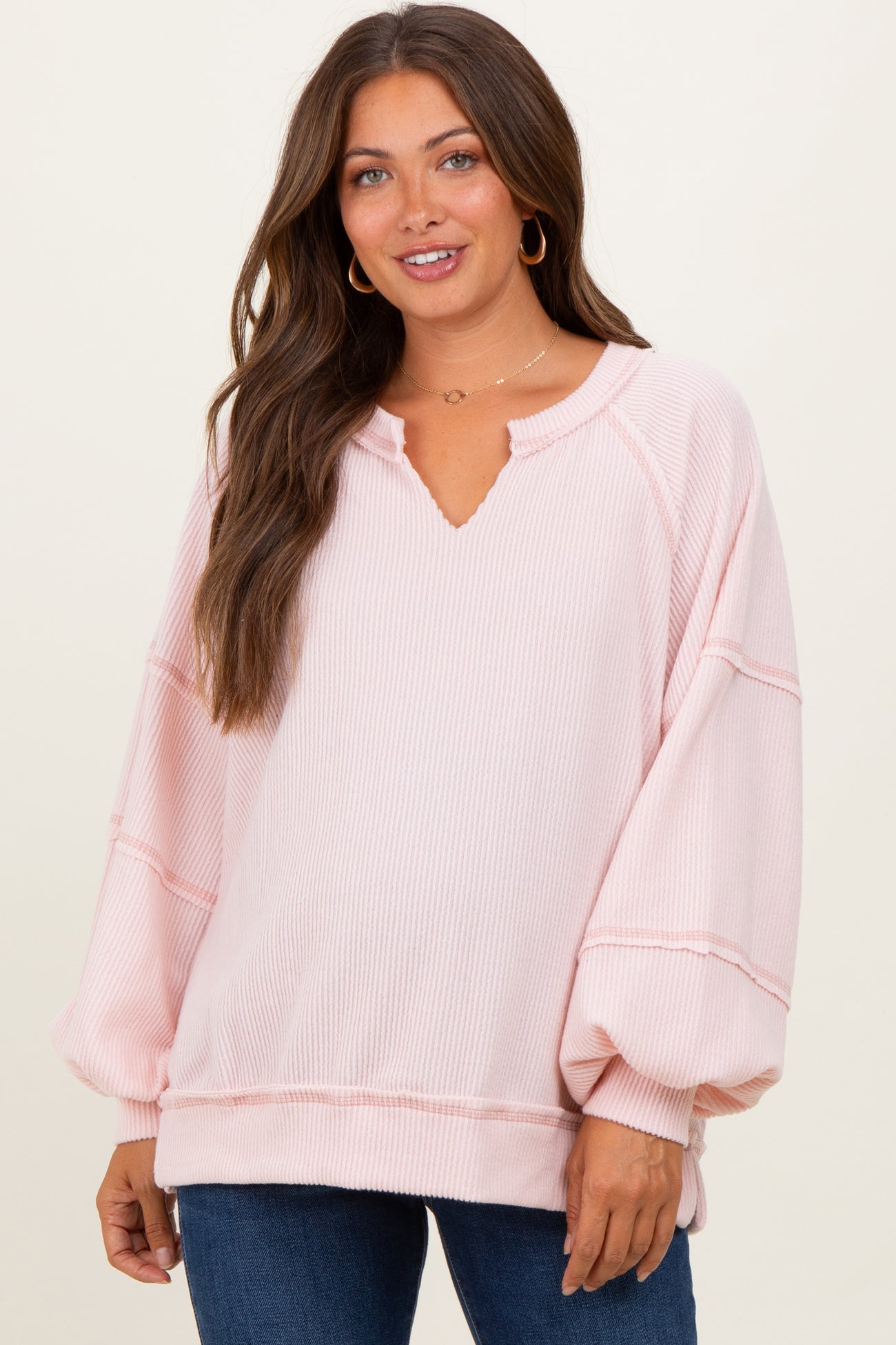 woman wearing a light pink maternity pullover with a v-neck and balloon sleeves