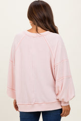 woman wearing a light pink oversized maternity sweater with balloon sleeves and ribbed texture, view from the back