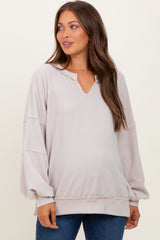 woman wearing a light taupe ribbed maternity top with a v-neck and long sleeves, showing her baby bump
