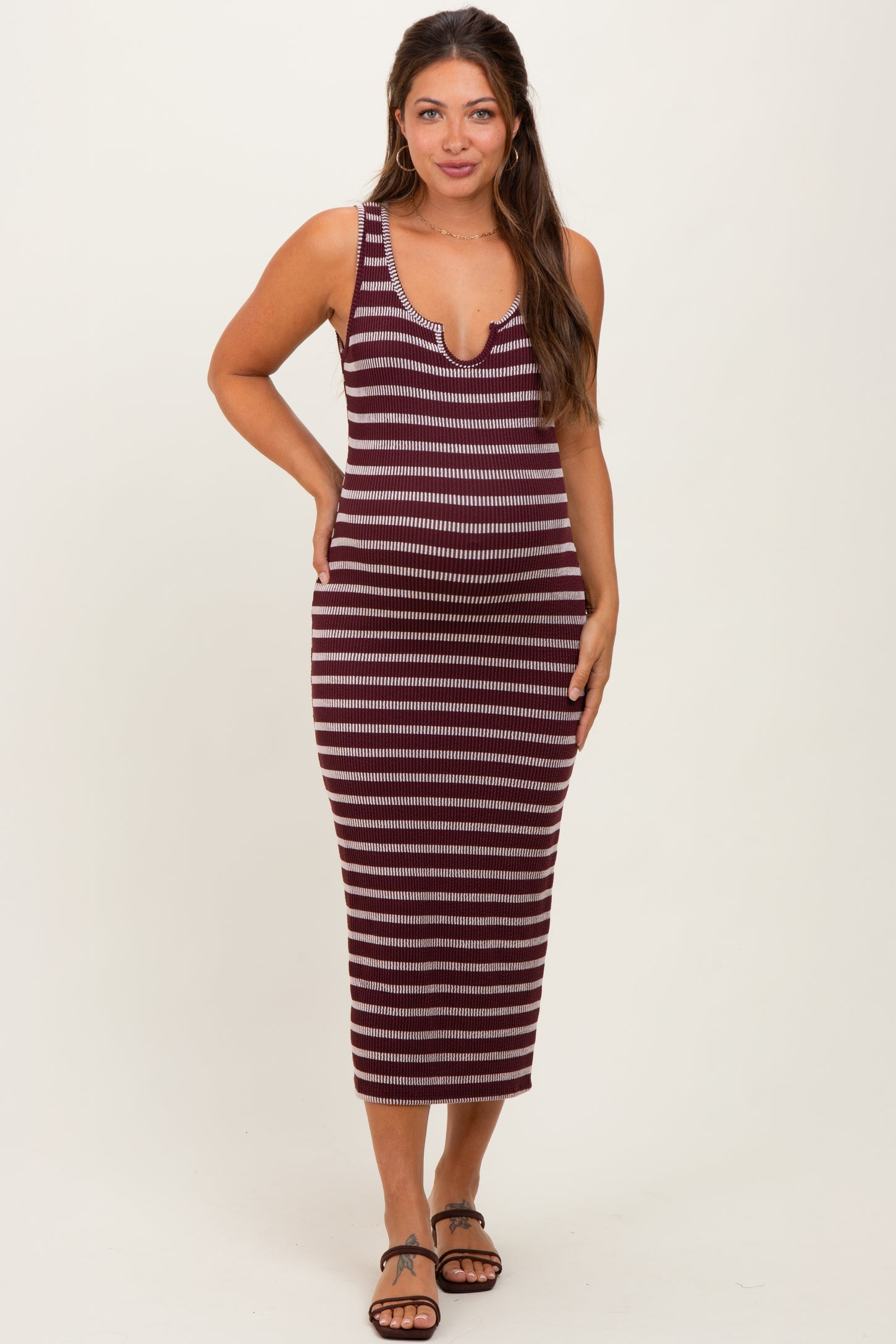 woman wearing a burgundy and cream striped maternity tank dress with a deeper v-neckline and a fitted silhouette