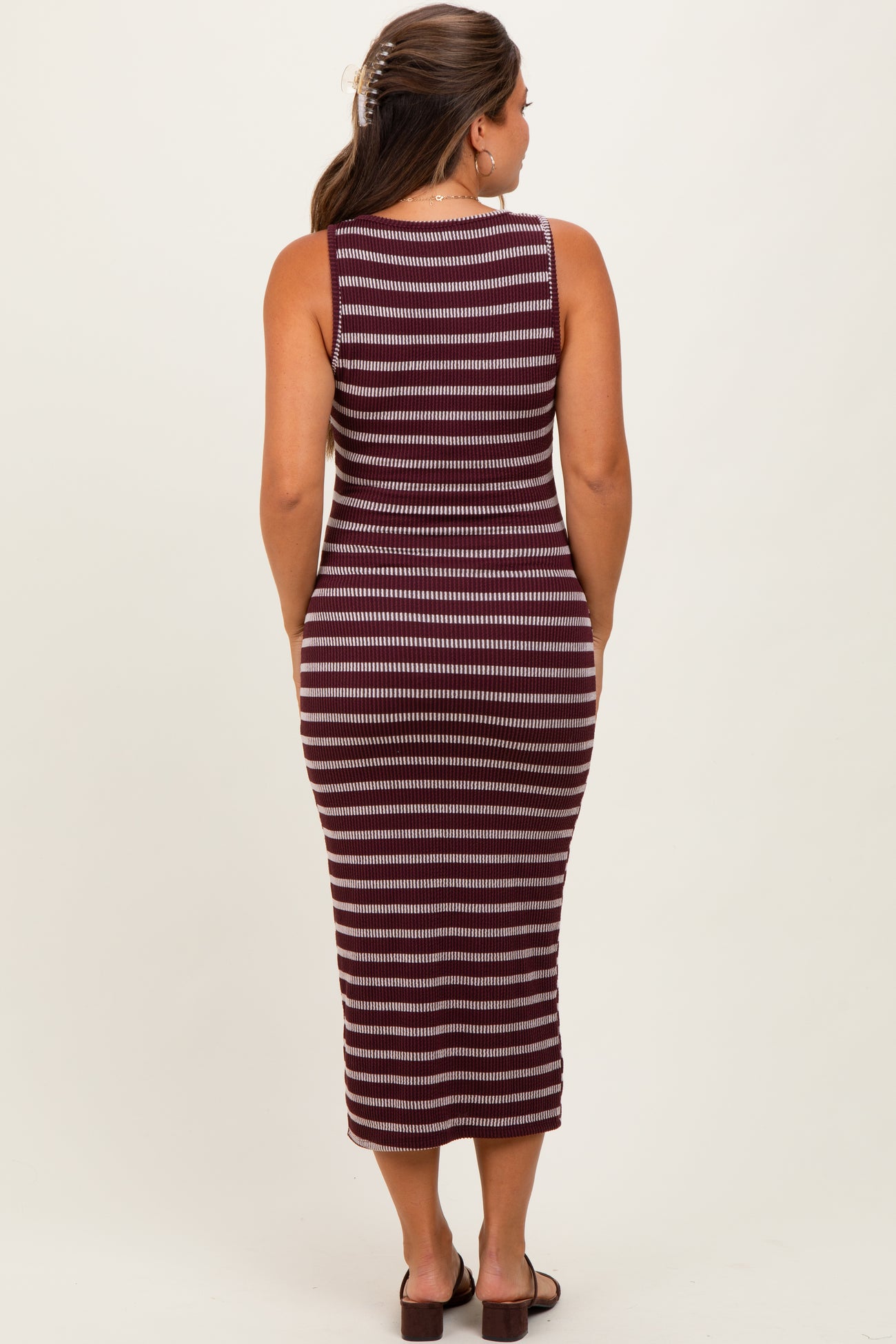 woman wearing a maroon and white striped maternity dress, fitted style, showing a side view of her baby bump