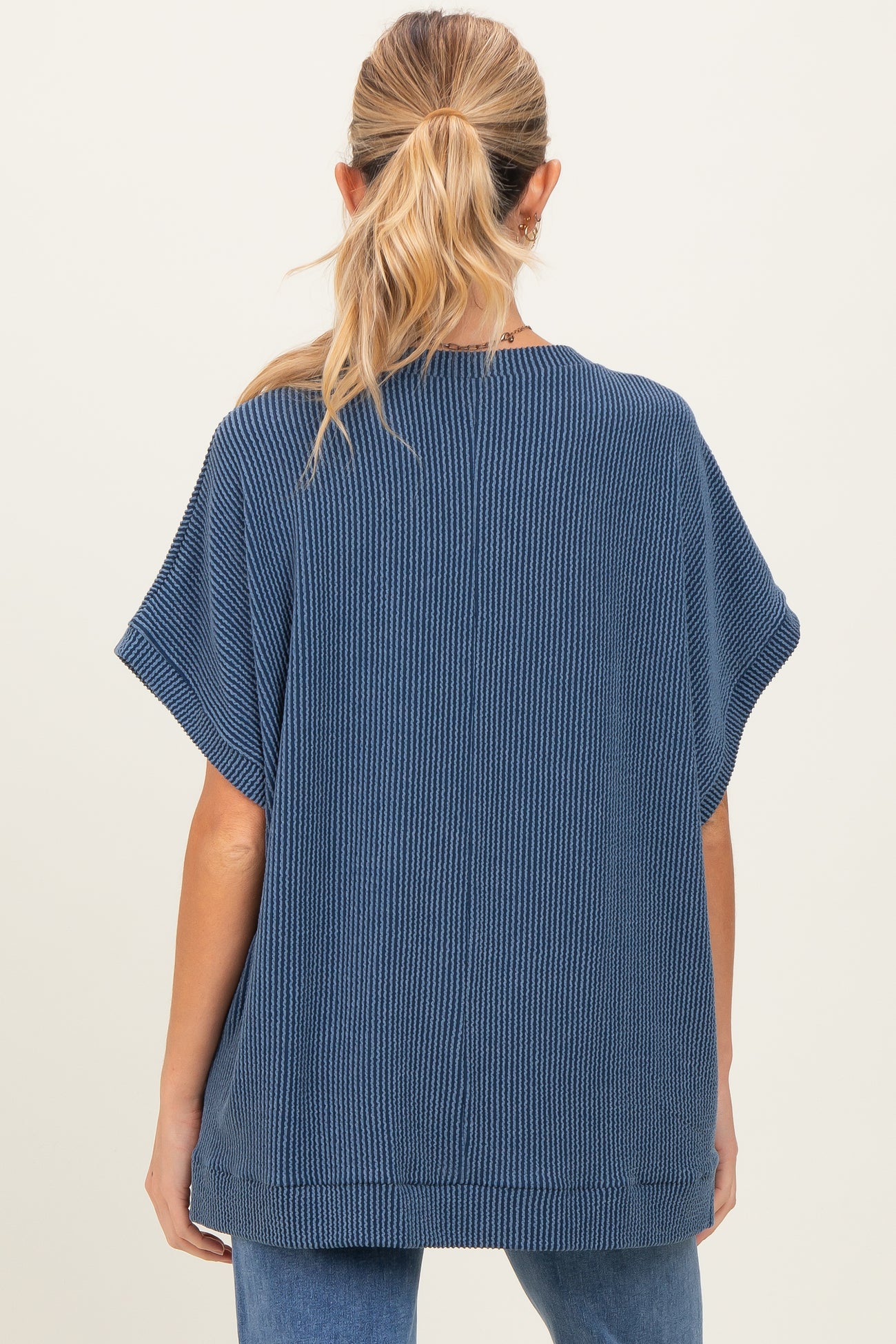 woman wearing a navy blue oversized maternity top with short sleeves, viewed from the back