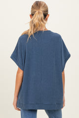 woman wearing a navy blue oversized maternity top with short sleeves, viewed from the back