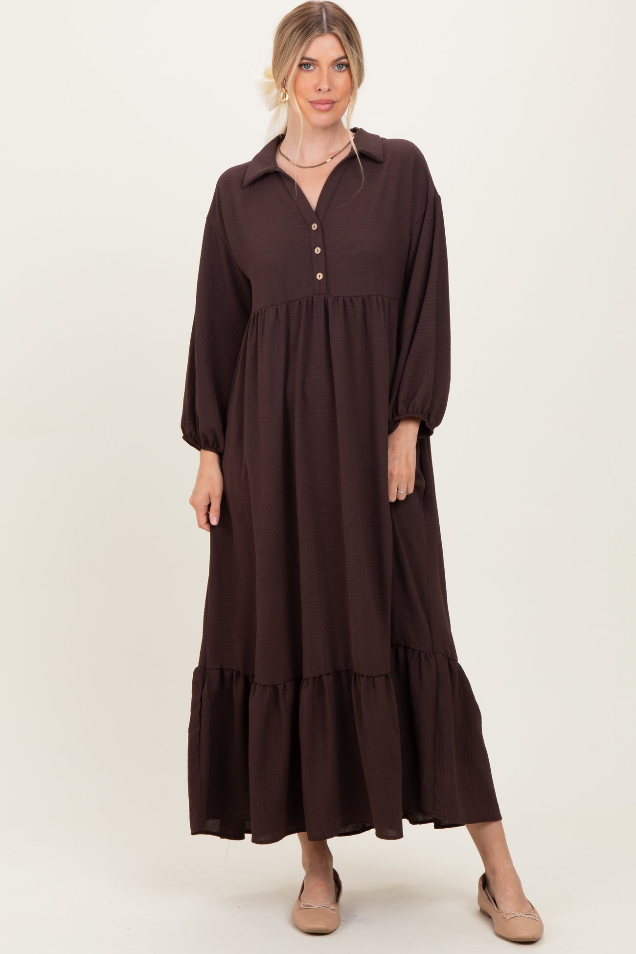 woman wearing a dark brown long sleeve maxi dress with a button-down collar and tiered hem