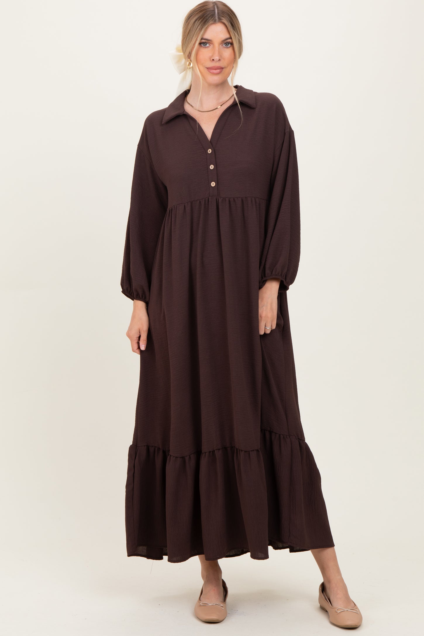 woman wearing a dark brown long sleeve maxi dress with a button-down collar and tiered hem