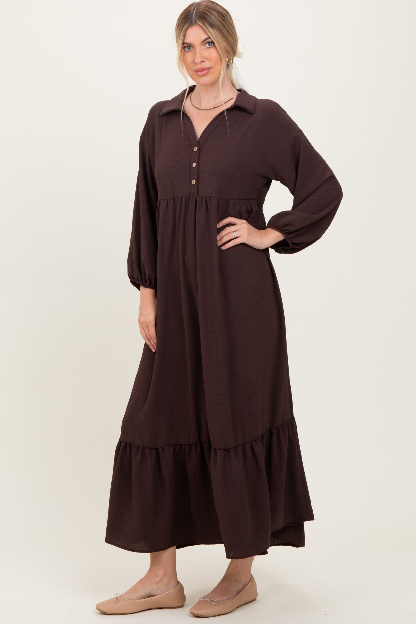 woman wearing a dark brown long sleeve button-up maxi dress with a tiered skirt