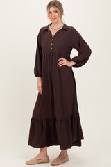 woman wearing a dark brown long sleeve button-up maxi dress with a tiered skirt