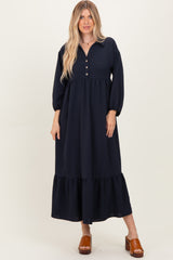 woman wearing a navy blue long sleeve button-up maxi dress with a tiered hem and puff sleeves