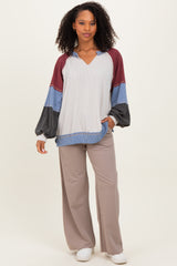 woman wearing a multi-colored long sleeve top with a v-neck and loose fit, paired with light brown wide-leg pants