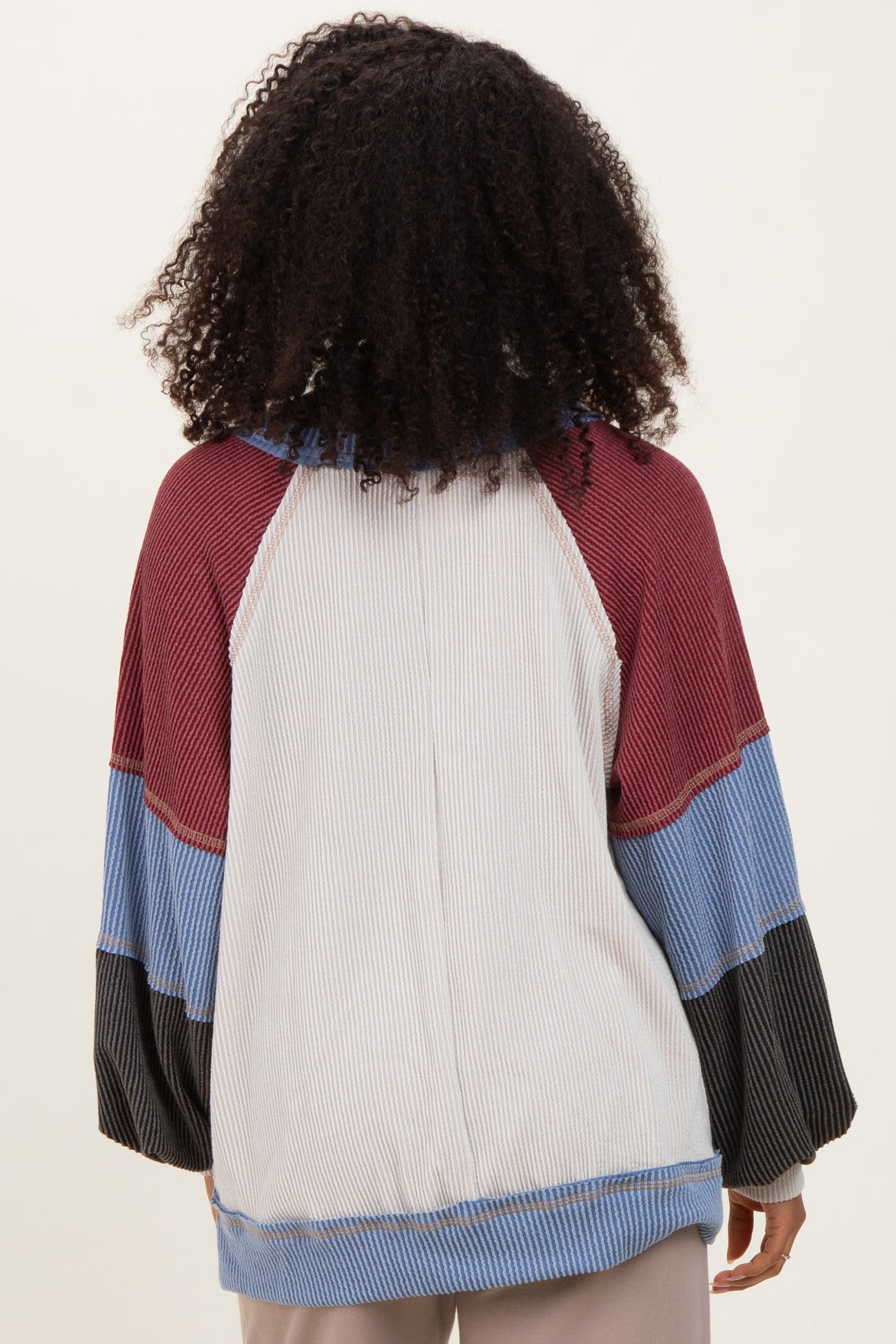 woman wearing a multicolor striped pullover with a hood and raglan sleeves, shown from the back