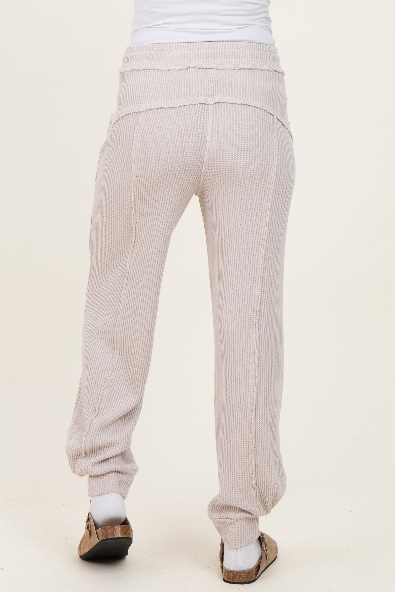 woman wearing light pink ribbed maternity joggers seen from the back