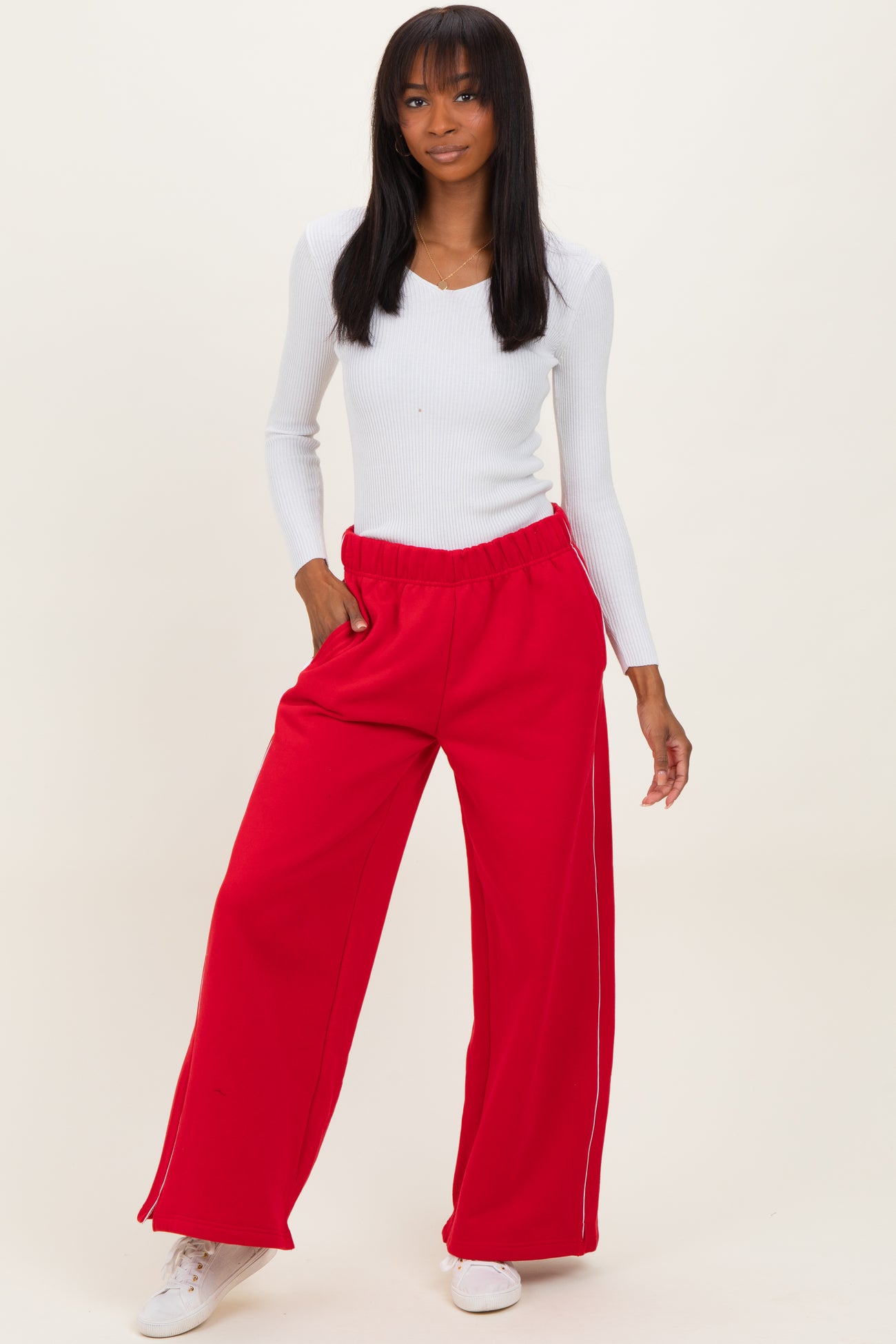woman wearing a white long sleeve ribbed top and red wide-leg pants with side pockets and white detailing