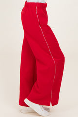 woman wearing red wide-leg pants with white piping and white sneakers