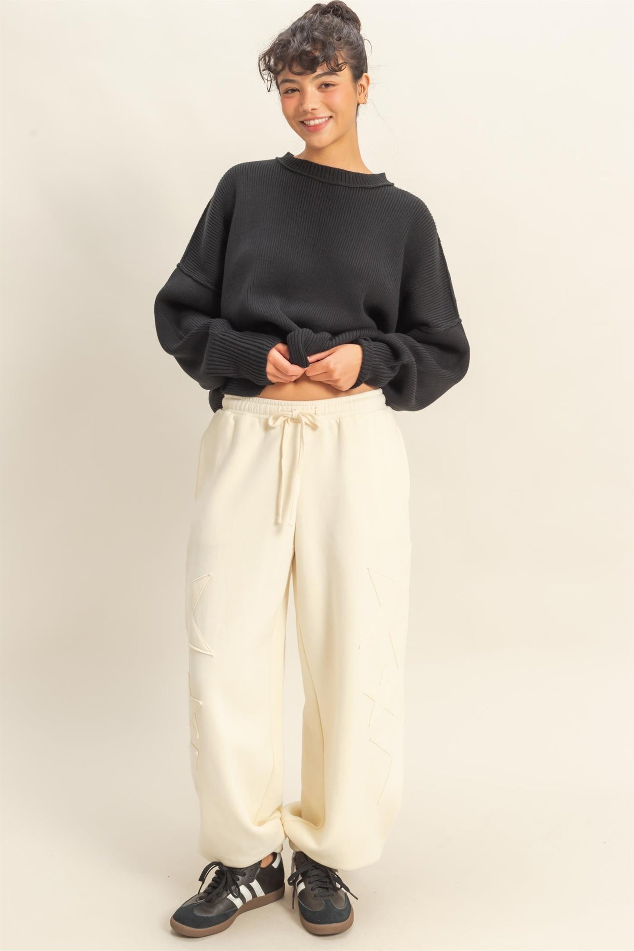 woman wearing a black oversized sweater and cream drawstring sweatpants with a relaxed fit