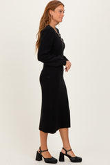 woman wearing a black ribbed midi dress with puff sleeves and walking in black block-heeled shoes