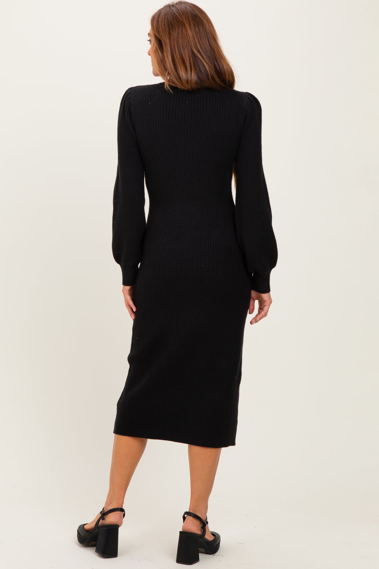 woman wearing a black ribbed midi dress with long puff sleeves and a fitted silhouette, viewed from the back