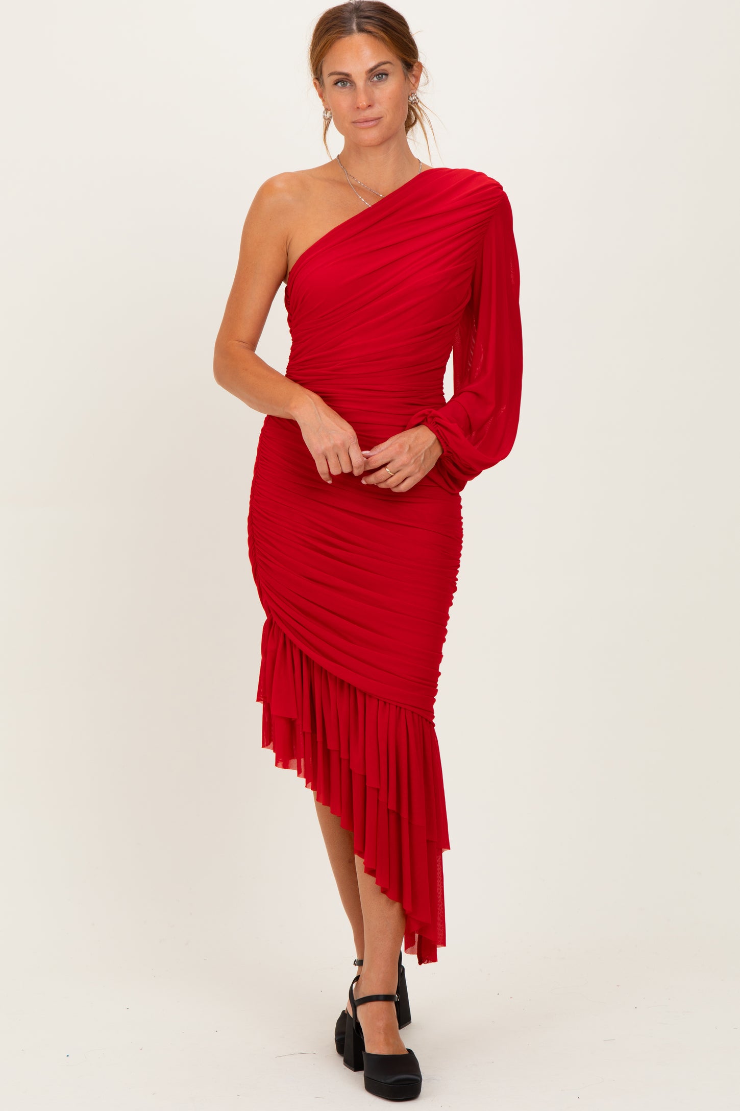 woman wearing a red one-shoulder ruched dress with a ruffled hem and a puff sleeve