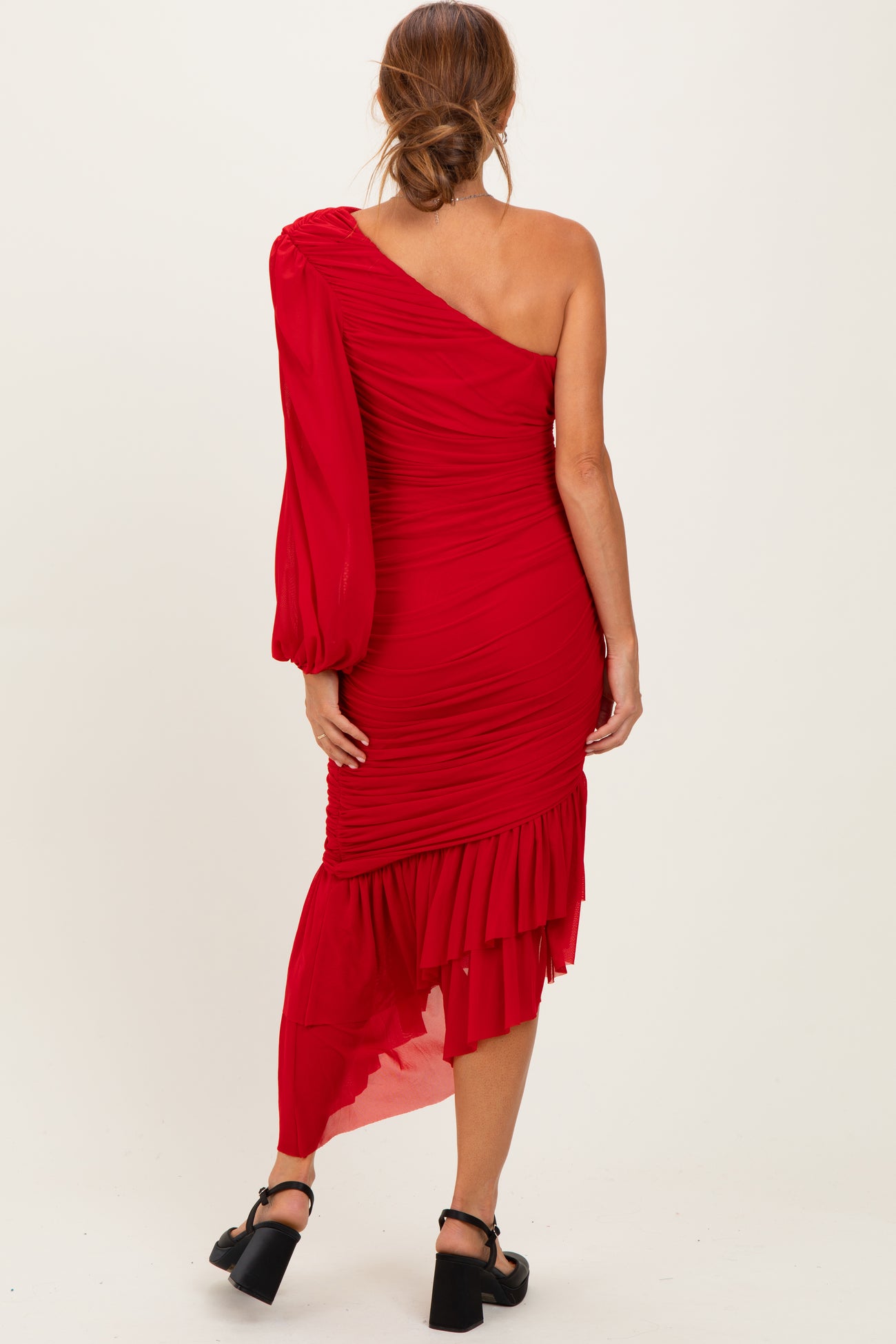 woman wearing a red one-shoulder ruched dress with a flounced hem and long sleeve details