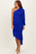 woman wearing a royal blue one-shoulder ruched dress with a draped hem and long sleeve detail