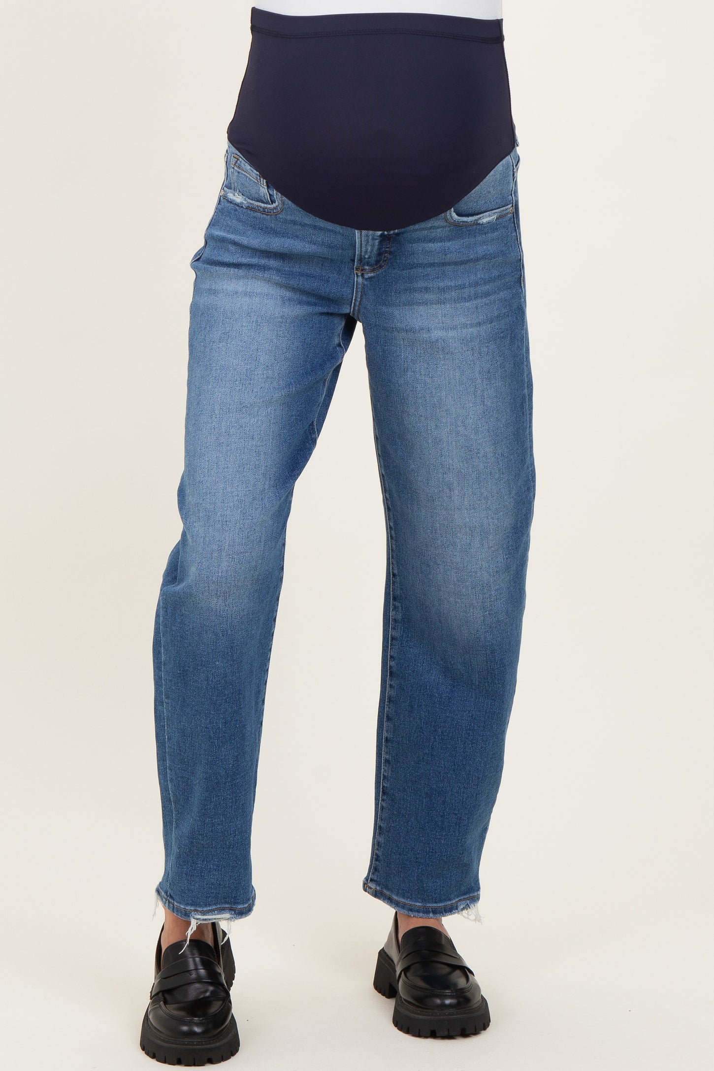 woman wearing a pair of light blue maternity jeans with a dark waistband, featuring a relaxed fit and slightly frayed hem