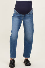woman wearing a pair of light blue maternity jeans with a dark waistband, featuring a relaxed fit and slightly frayed hem