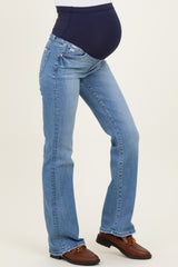 woman wearing a pair of light blue maternity jeans with a dark blue over-the-bump waistband and a visible baby bump
