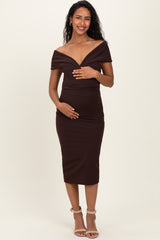 woman wearing a brown off-the-shoulder maternity dress and holding her baby bump