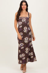 woman wearing a floral print brown maxi dress with spaghetti straps and a fitted silhouette
