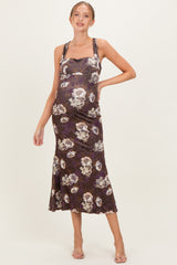 woman wearing a dark floral print maternity dress with a fitted bodice and flared hem, showcasing her baby bump
