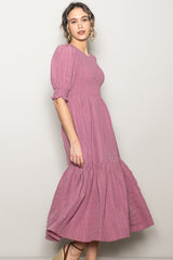 woman wearing a rose pink puff sleeve midi dress with smocked bodice and tiered skirt
