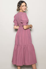 woman wearing a dusty pink midi dress with puff sleeves and a tiered skirt, shown from the back