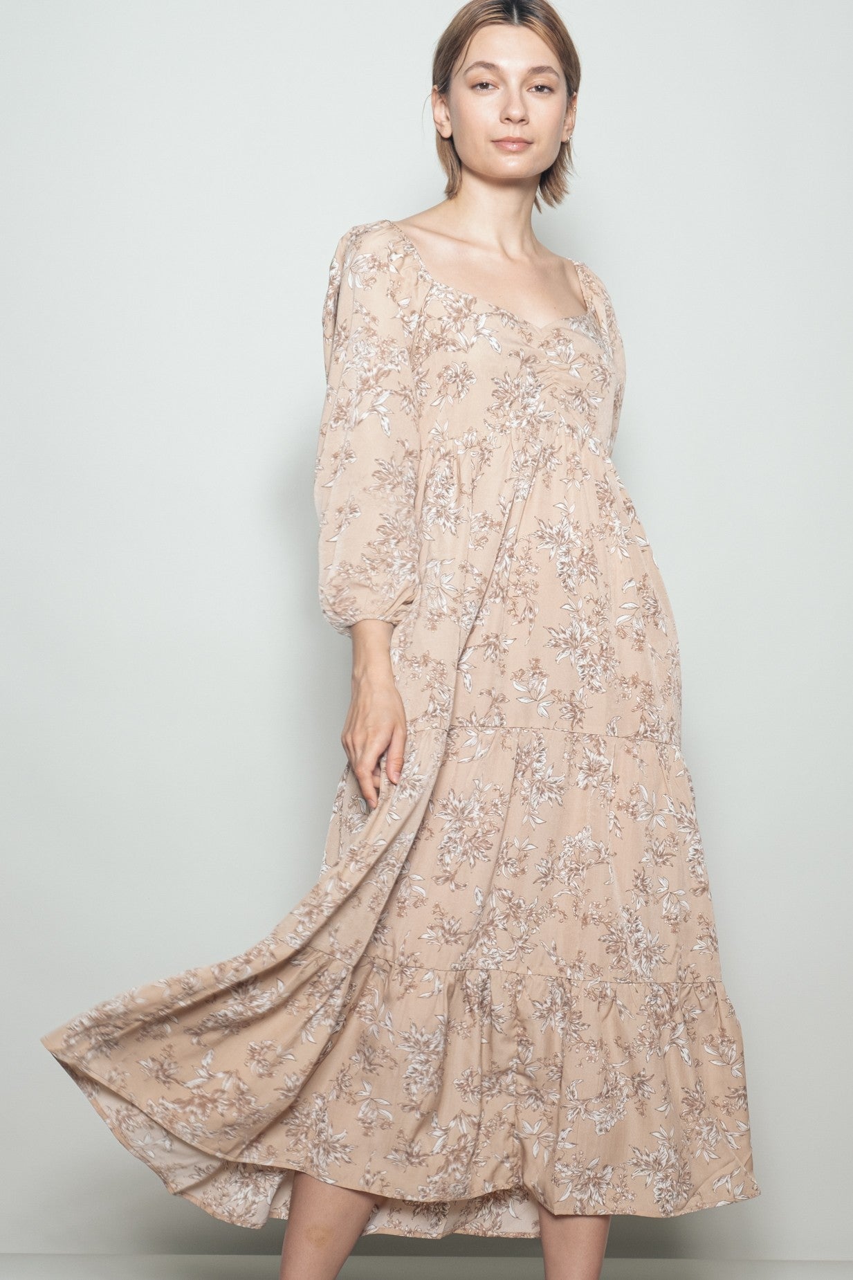 woman wearing a beige floral tiered maxi dress with long sleeves and a square neckline
