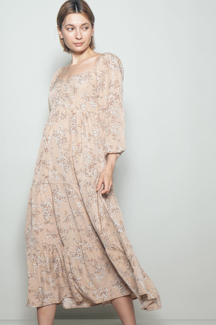 woman wearing a light beige floral maxi dress with puffed sleeves and a square neckline