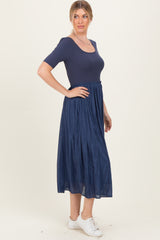 woman wearing a navy blue short sleeve dress with a fitted top and flowy midi skirt, paired with white sneakers