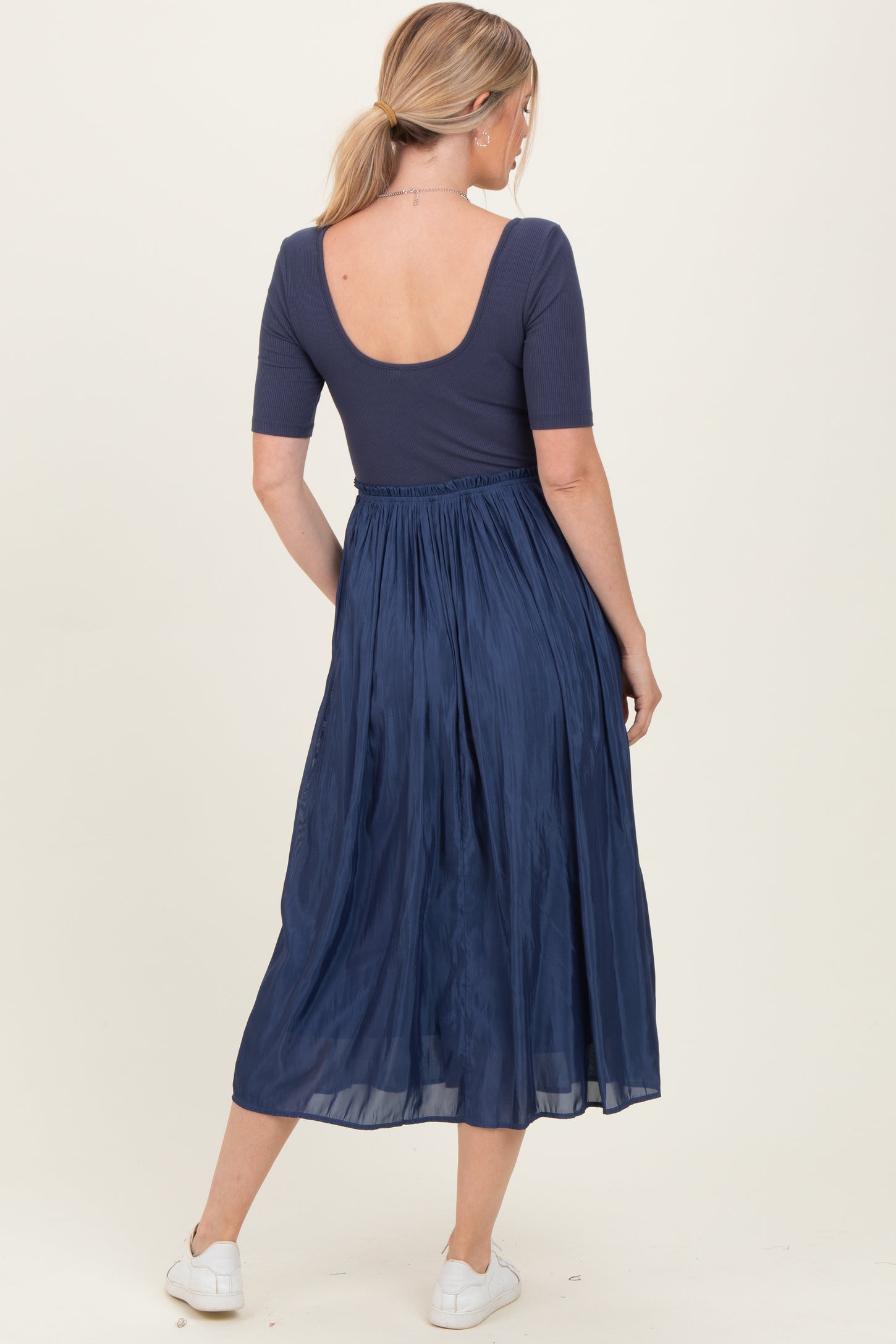 woman wearing a navy blue scoop back top paired with a flowy midi skirt, seen from the back