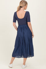 woman wearing a navy blue scoop back top paired with a flowy midi skirt, seen from the back