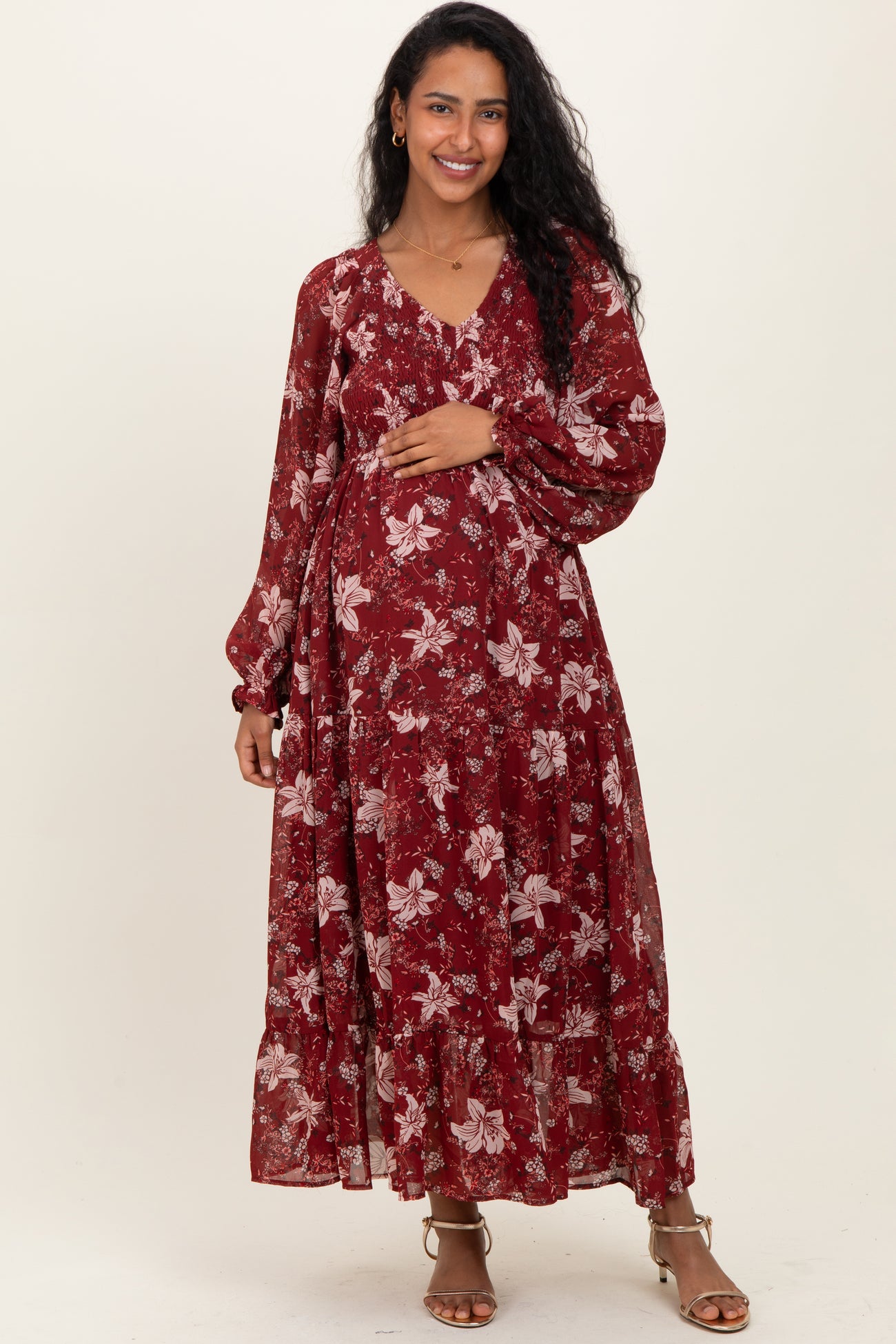 woman wearing a burgundy floral maxi maternity dress and holding her baby bump