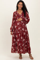 woman wearing a burgundy floral maxi maternity dress and holding her baby bump