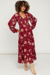 woman wearing a floral burgundy maternity maxi dress with long sleeves and a v-neckline, showing her baby bump
