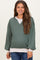 woman wearing a green maternity sweatshirt with a white hem and v-neckline, showing her baby bump
