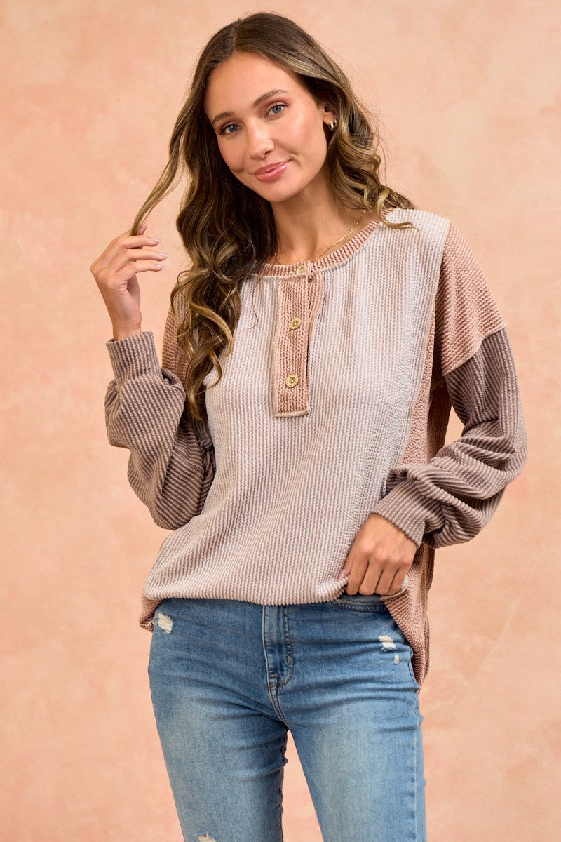 woman wearing a color-blocked long sleeve knit top with buttons and distressed jeans