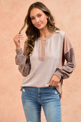 woman wearing a color-blocked long sleeve knit top with buttons and distressed jeans