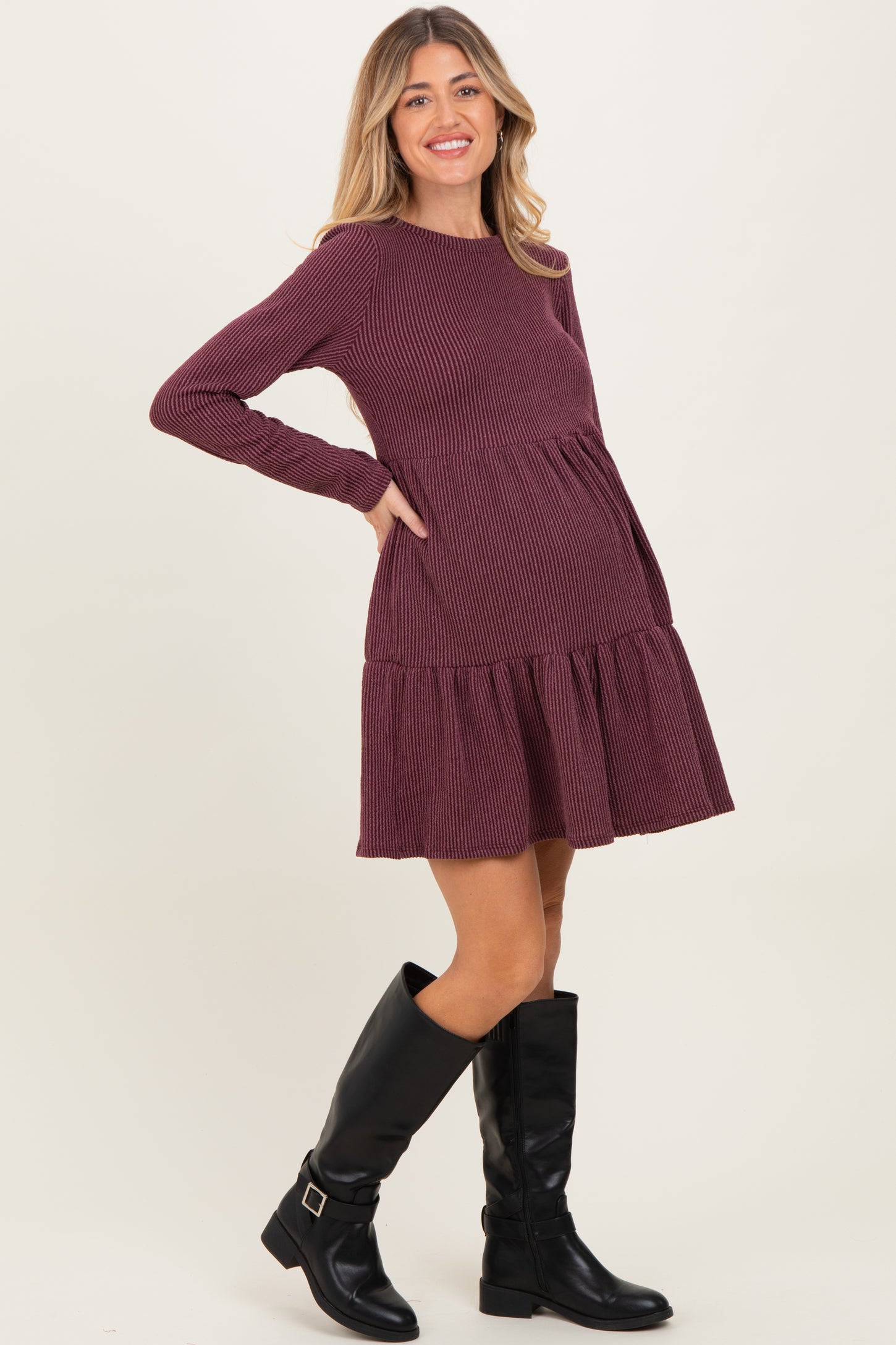 woman wearing a burgundy ribbed long sleeve maternity dress with a tiered skirt and a visible baby bump
